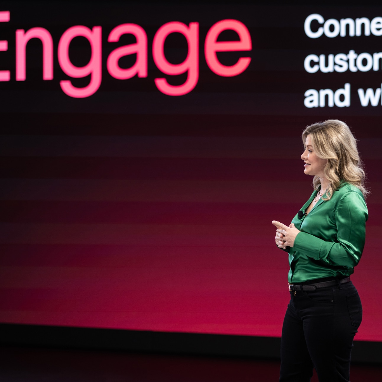 A smiling individual in a green shirt speaks onstage at WebexOne.