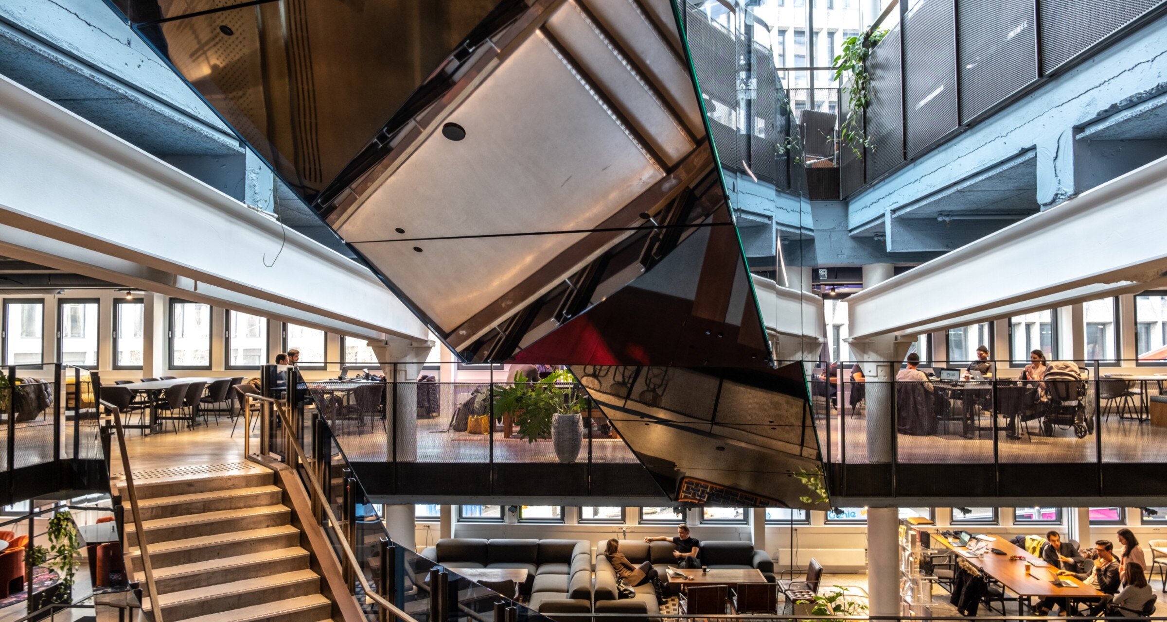The Rebel building. The photo shows people connecting in various meeting areas with couches, tables, etc. on multiple floors.